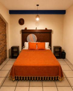 a bedroom with a large bed with an orange blanket at Hotel Frida in Mexico City