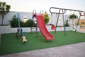 a playground with a slide and swings on grass at La mira chalet in Madaba