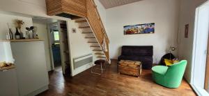 a living room with a staircase and a green chair at Chalet spacieux proche mer in Longeville-sur-Mer +23 photos