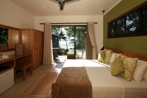 a bedroom with a bed and a desk and a window at Le Repaire - Boutique Hotel & Restaurant in La Digue