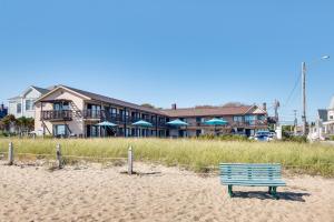 a blue bench sitting on the sand on the beach at Old Orchard Beach Condo: Steps From the Beach! in Old Orchard Beach