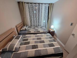 two beds in a bedroom with a window at Dpto 2D2B Barlovento Brisas del Sol in Talcahuano