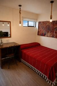 a bedroom with a red bed and a desk at Hotel Frida in Mexico City