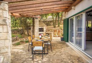 a patio with a table and chairs under a wooden pergola at Kuća za odmor Olea in Stari Grad