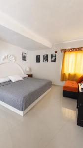 a white bedroom with a bed and a yellow curtain at Hotel Casa Xicun in Tepoztlán