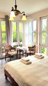 a bedroom with two beds and chairs and windows at Agroturystyka Rawiczówka in Brzeżno