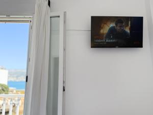 a flat screen tv on a wall next to a window at Windmill Rooms in Antiparos