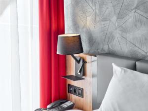 a lamp on a night stand next to a bed at ibis Styles Nowy Targ in Nowy Targ