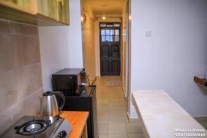 a kitchen with a stove and a microwave and a door at Mbaaria House, Meru in Meru