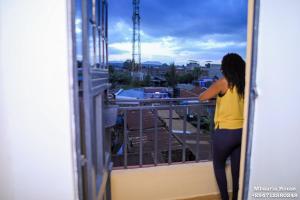 a woman standing on a balcony looking at her cell phone at Mbaaria House, Meru in Meru