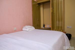 a bedroom with a white bed with towels on it at Mbaaria House, Meru in Meru