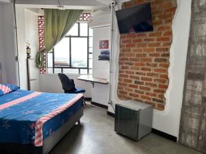 a bedroom with a bed and a brick wall at La Curva in Cali