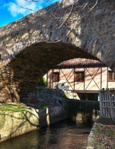a stone bridge over a river with a building at Hostal Dobe in Benavides