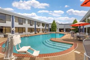 a pool at a hotel with chairs and an umbrella at Best Western Plus Madison-Huntsville Hotel in Madison
