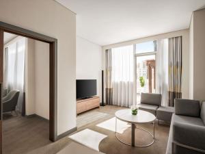 a living room with a couch and a tv and a table at Novotel Bur Dubai - Healthcare City in Dubai