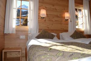 a bedroom with a bed with white sheets and two windows at Hôtel-Restaurant Mélèze Grimentz in Grimentz