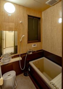 a bathroom with a tub and a toilet and a sink at 笑福邸 in Shiogama +24 photos
