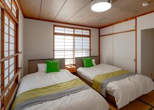 two beds in a room with green pillows at 笑福邸 in Shiogama