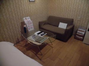 a living room with a couch and a glass table at ホテル タイムレス 明石 男塾ホテルグループ in Akashi