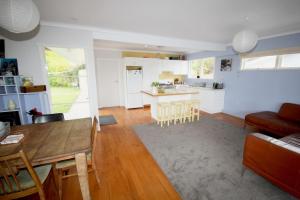 a living room and kitchen with a table and chairs at Waiwera Beach GetAway in Waiwera