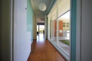 a hallway with glass doors and a hallway with wood floors at Waiwera Beach GetAway in Waiwera