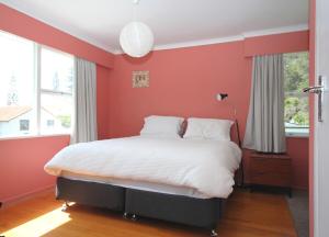 a bedroom with red walls and a bed with white sheets at Waiwera Beach GetAway in Waiwera +9 photos