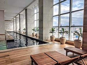 a large pool with plants in a building with windows at The Cittyplex Home Osasco Estilo & Conforto in Osasco