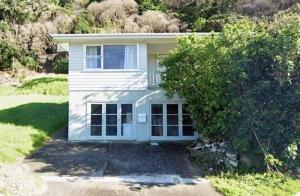 a small white house with a tree in front of it at Waiwera Beach GetAway in Waiwera