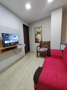 a living room with a red couch and a flat screen tv at Recanto dos sabias AP01 in Conservatória