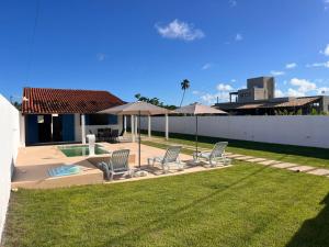 a yard with chairs and umbrellas and a pool at Califeira do Patacho in Pôrto de Pedras