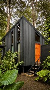 a black tiny house with a wooden door at KAÑIK APART HOTEL in Puerto Viejo