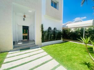 a white house with a yard with grass at Villa haut-standing avec piscine à Hammamet in Yasmine