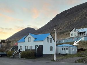 a white house with blue roofs in front of a mountain at Krókur Guesthouse in Patreksfjörður