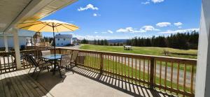 a balcony with a table and an umbrella at The Great Cabot Lodge in Baddeck