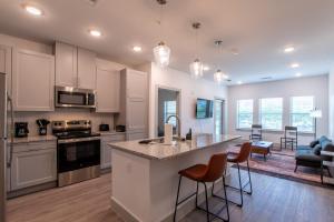 a kitchen with white cabinets and a kitchen island with bar chairs at Luxury McKinney Resort Stay Near Universal Kids with Pool & Gym in McKinney