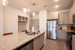 a kitchen with white cabinets and a stainless steel refrigerator at Luxury McKinney Resort Stay Near Universal Kids with Pool & Gym in McKinney