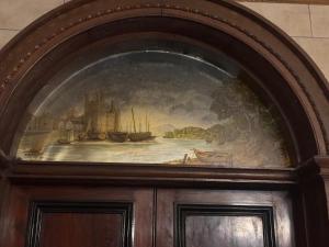 a painting over a wooden door with a painting of a ship at Plas Glynllifon Mansion in Caernarfon