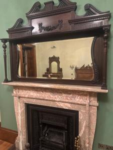 a mirror sitting on top of a fireplace at Plas Glynllifon Mansion in Caernarfon