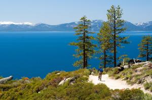 a man riding a bike on a trail next to a lake at Tahoe Keys #214 in South Lake Tahoe
