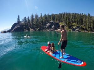 a man and two children on a paddle board in the water at Tahoe Keys #214 in South Lake Tahoe