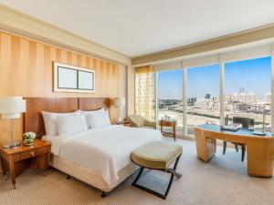 a hotel room with a bed and a desk and window at Mövenpick Hotel Al Khobar in Al Khobar