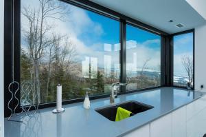 a kitchen with a sink and a large window at Secret Charlevoix - River View & Spa in Les Éboulements +46 photos