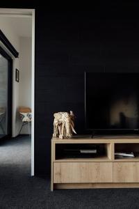 a flat screen tv sitting on top of a wooden entertainment center at Kais Retreat in Punakaiki
