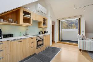 a kitchen with wooden cabinets and a large window at Gibbston Hideaway in Gibbston