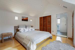 a white bedroom with a bed and a glass door at Gibbston Hideaway in Gibbston