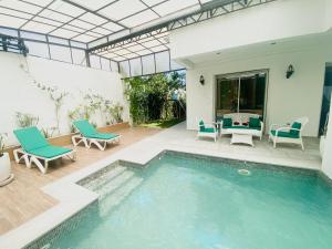 a patio with a pool and chairs and a table at Villa haut-standing avec piscine à Hammamet in Yasmine