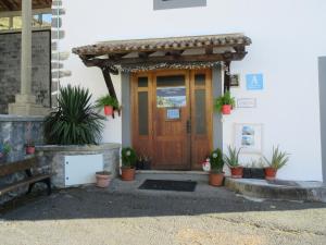 Albergue Ambiental de Beizama في Beizama: باب أمام منزل به نباتات الفخار