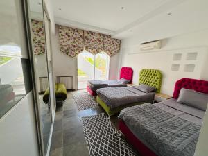 a room with three beds and chairs and a window at Villa haut-standing avec piscine à Hammamet in Yasmine +28 photos