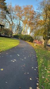 a road in a park with leaves on the grass at Grachtenpracht Boutique in Breda