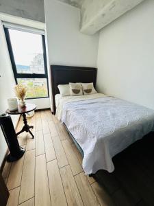 a bedroom with a bed and a table and a window at Cozy Apartment 4 degrees north in Las Victorias